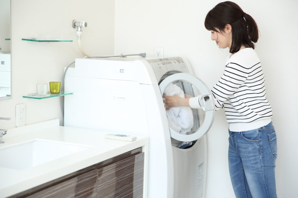 カーペットを洗濯するため家庭用洗濯機に入れようとしている女性