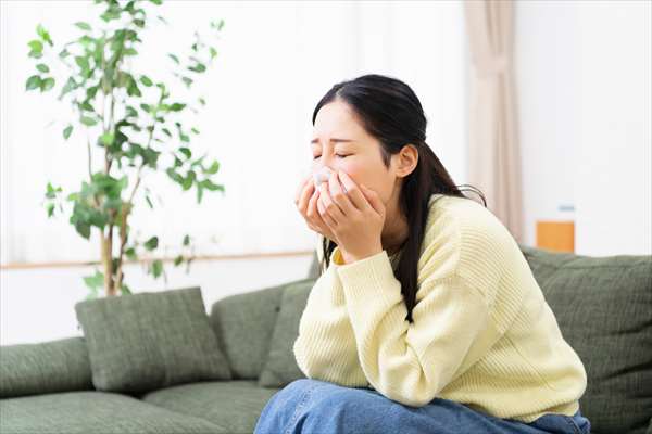 ハウスダストによるアレルギー症状で鼻をかむ女性