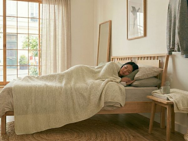 ナチュラルインテリアのベッドで横になる女性