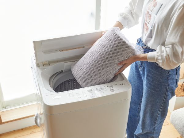 イブルラグをたたんで洗濯機に入れている