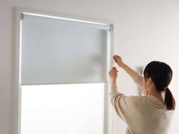 ロールスクリーンを上下させる女性