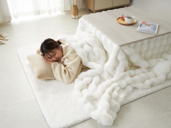 かわいい白のこたつ布団に入って寝ている人