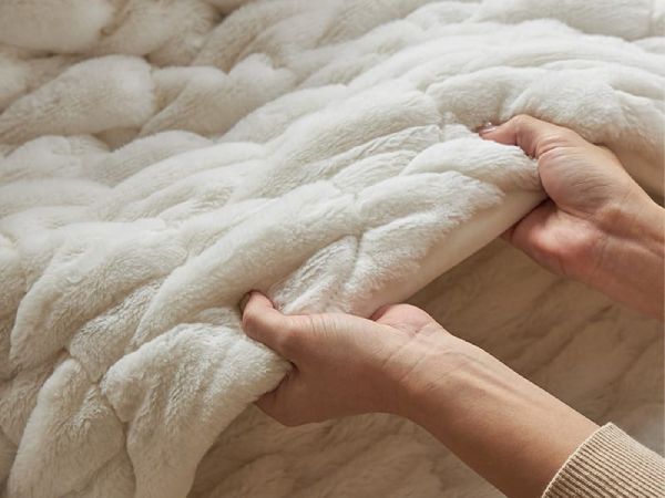 白のこたつ布団に触れる手